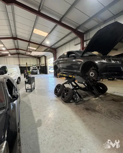 A Jaguar saloon on the scissor lift with all four wheels off and the hubs exposed