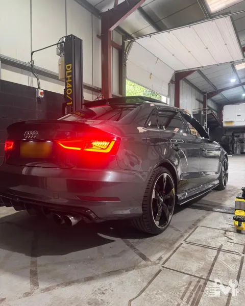 An Audi saloon raised on the lift with the rear lights lit during a pre-MOT inspection