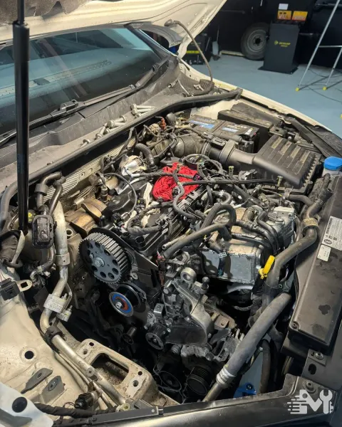 Engine bay opened up for servicing, with the cam pulley and timing belt exposed