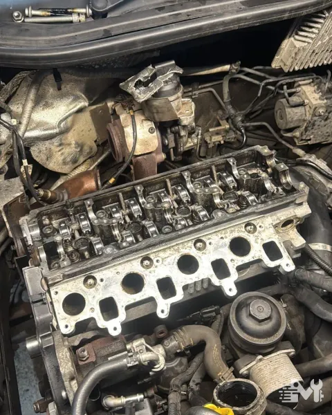 A diesel cylinder head lifted off in the engine bay, valves and rocker gear on show