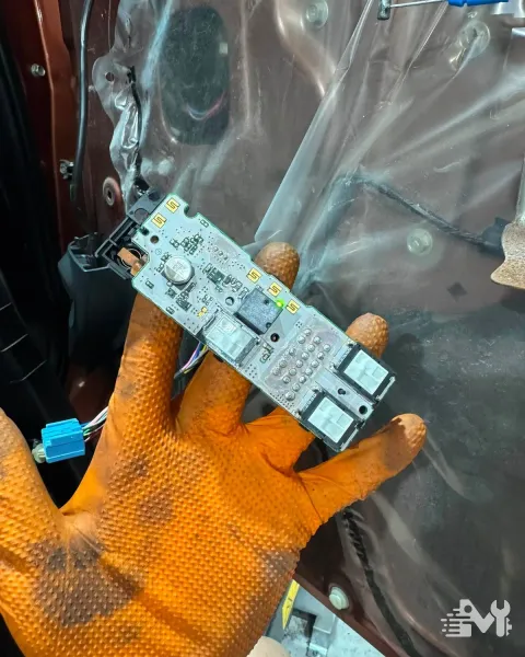 A car door control module circuit board removed for repair