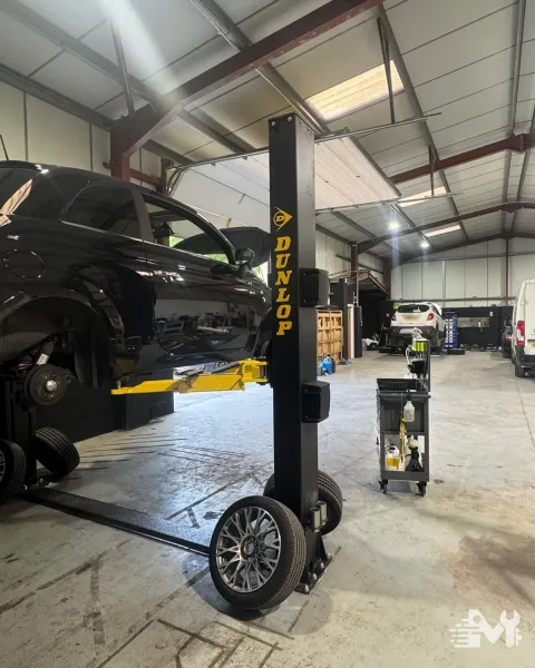 A car up on the lift with a wheel off and the alloy stood on the floor for a tyre change