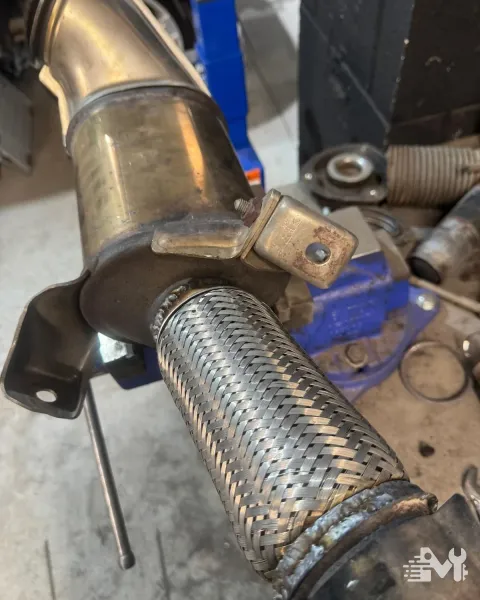 A new braided flexi joint welded into an exhaust downpipe, held in the bench vice