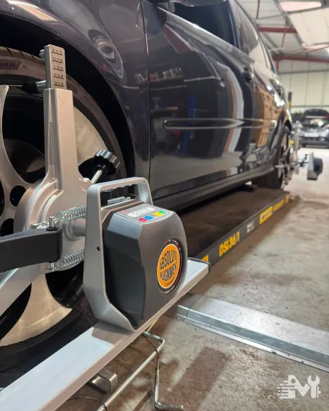 Four wheel alignment equipment clamped to a car's wheel on the alignment ramp